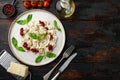 Appetizing ravioli with tomato sauce cheese and basil with basil parmesan and tomatoe on white plate on old dark wooden table