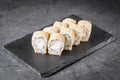 Appetizing sushi roll with Philadelphia tofu sesame cheese on a black stone plate