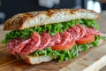 Appetizing Sandwich with baguette, Italian cured mortadella sausage, lettuce and tomatoes on a wooden cutting board. Fast food,