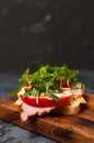 Appetizing sandwich with ham or balyk, arugula, cheese, tomatoes and mayonnaise on a cutting board side view Royalty Free Stock Photo