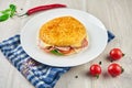 Appetizing sandwich in Italian tortilla focaccio with ham, cheese, onions, tomatoes and lettuce on a white plate on a wooden Royalty Free Stock Photo
