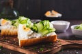 Appetizing sandwich with ricotta, cucumber slices, boiled egg and sesame seeds on a board