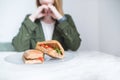 The appetizing sandwiches lie on the table in a plate on the background of a woman. The woman dishes with sandwiches