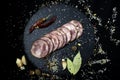 Appetizing sausage sliced on a slate board on a black background with spices and chilli selective artistic focus