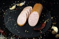 Appetizing sausage sliced on a slate board on a black background with spices and chilli selective artistic focus