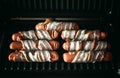 Appetizing sausages wrapped in bacon are grilled on a electric grill Royalty Free Stock Photo