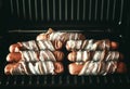 Appetizing sausages wrapped in bacon are grilled on a electric grill Royalty Free Stock Photo