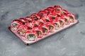 Appetizing set of California sushi rolls in red tobiko caviar with salmon, tuna and eel in a white plate on a gray background. Royalty Free Stock Photo