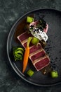 Appetizing slightly fried tuna with grilled vegetables close-up, traditional Italian cuisine, gray background, a dish