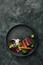 Appetizing slightly fried tuna with grilled vegetables close-up, traditional Italian cuisine, gray background, a dish