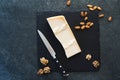 An appetizing solid cheese on a black plate on a gray stone background Royalty Free Stock Photo