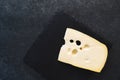 An appetizing solid cheese on a black plate on a gray stone background Royalty Free Stock Photo