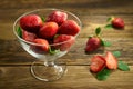 Appetizing strawberries in a glass bowl on old wooden boards. Rustic style.