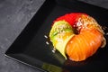 Appetizing sushi roll donut with salmon on a black stone plate Royalty Free Stock Photo