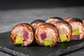 Appetizing sushi roll with tuna salmon escolar crab and avocado on a black stone plate