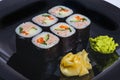 Appetizing sushi roll with tuna salmon escolar crab and avocado on a black stone plate