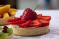 Appetizing tartlets with strawberry and various berrys and fruits are lying on a white tablecloth. Royalty Free Stock Photo