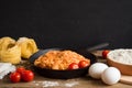 Appetizing traditional classic Italian pasta with tomato sauce and basil in a black frying pan on a wooden table. Space for text