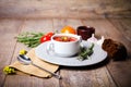 Appetizing Ukrainian traditional borscht in a white plate on old table with vegetable on a wooden background.