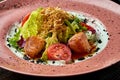 Appetizing warm salad with baked salmon, cherry tomatoes, lemongrass and white sauce, served in a white plate on a wooden