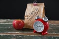 Apple, alarm clock and lunch bag on wooden table Royalty Free Stock Photo
