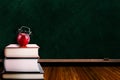 Apple Alarm Clock on Stack of Books and Chalkboard Background