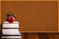 Apple Alarm Clock on Stack of Books and Corkboard Background