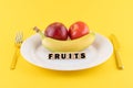 Apple, a banana and a tomato on a plate and the word 'fruits' written on wooden blocks