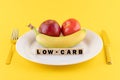 Apple, a banana and a tomato on a plate and the word 'low-carb' written on wooden blocks Royalty Free Stock Photo