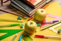 Apple, book and colorful school stationery items on a yellow background. Concept back to school