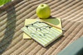 Apple book pencil glasses notebook on garden chair outdoor. Backyard study