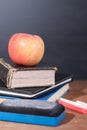 Apple, Books and Chalks with Blackboard Background