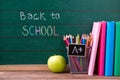 Apple, books and colored pencils on the chalkboard with back to school written background Royalty Free Stock Photo