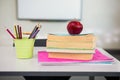Apple with books and desk organizer on table in classroom Royalty Free Stock Photo