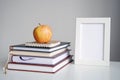 Apple on books, notebook, white frame. Back to school, study concept.