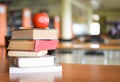 An apple on the books on the table with bookshelf in the library bookshelves background - Education learning concept book stack