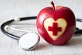 Apple with carved medical symbol of cross in heart with stethoscope, creative health and medical care concept Royalty Free Stock Photo