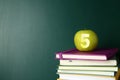 Apple with carved number five as school grade on books near green chalkboard, space for text Royalty Free Stock Photo