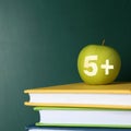 Apple with carved number five and plus symbol as school grade on books near green chalkboard, space for text Royalty Free Stock Photo