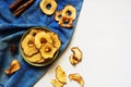 Apple chips and cinnamon on white wooden table. Homemade dry dehydrated fruit slices, autumn fall snack, healthy vegetarian diet