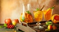 Apple cider cocktail with red oranges and spices in glasses and jug on table. Concept of autumn and winter drinks