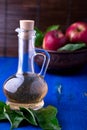 Apple cider vinegar in glass bottle on blue background. Red apples in brown bowl. Royalty Free Stock Photo