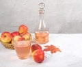 Apple cider vinegar, juice in a glass and a bottle of cider with apples in a wicker plate on a light table.