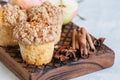 Apple cinnamon crumble muffins on a wooden board. White stone ba