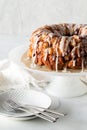 An apple cinnamon pull apart bread on a pedestal stand with dishes for serving.