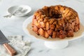 An apple cinnamon pull apart bread on a pedestal stand with dishes for serving.