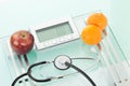 Apple,clementines with sethoscope on scales Royalty Free Stock Photo