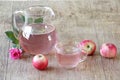 Apple compote in a transparent jug both fresh apples and a rose