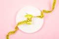 Apple core with measuring tape in place of the waist on a white plate on pink background. Diet, weigh loss, starvation, fitness Royalty Free Stock Photo