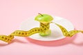 Apple core with measuring tape in place of the waist on a white plate on pink background. Diet, weigh loss, starvation, fitness Royalty Free Stock Photo